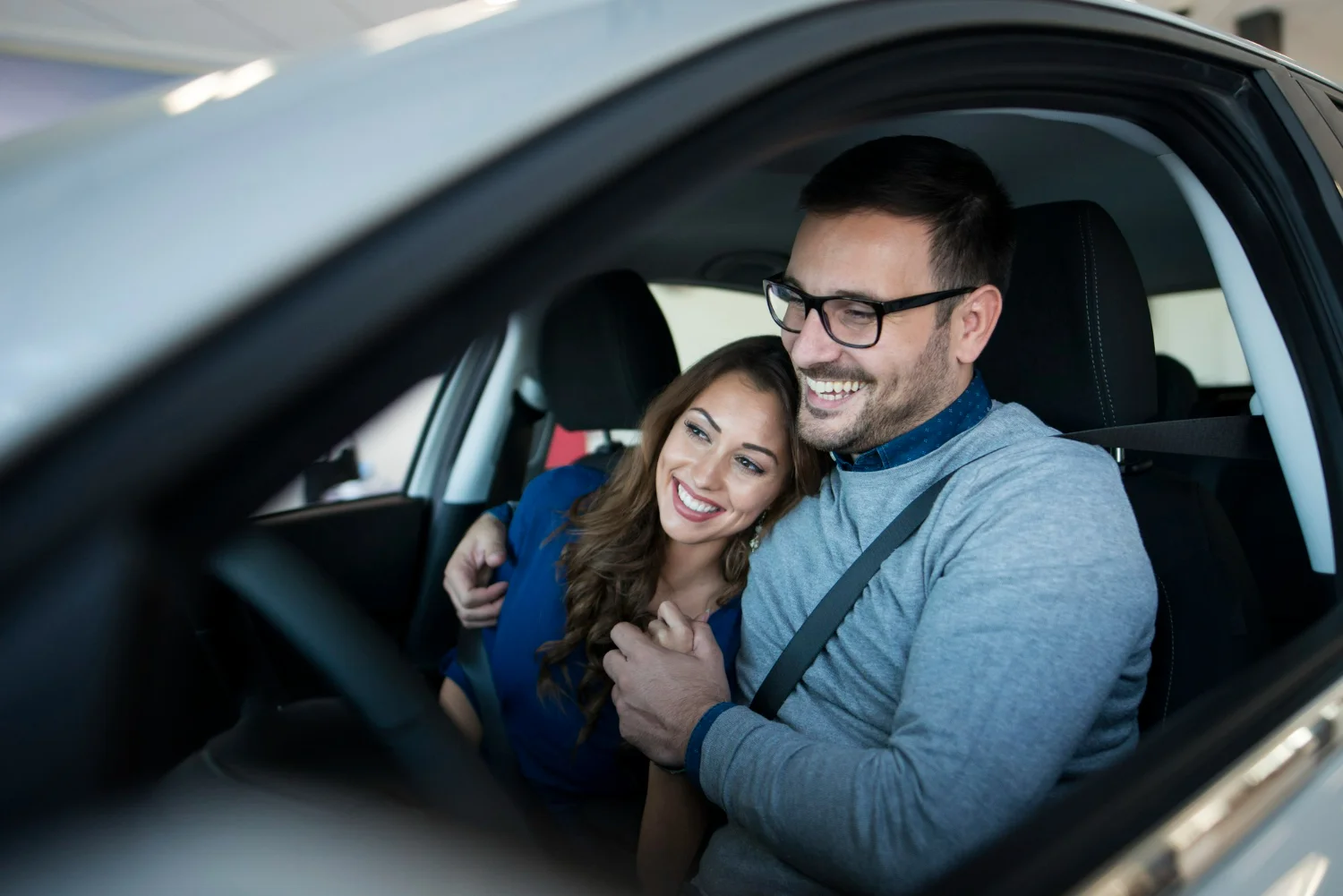 Casal sorridente dentro de carro representando planejamento com consórcio para primeiro carro